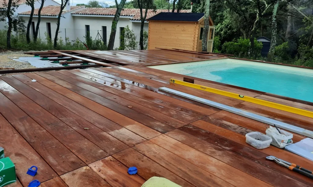 Terrasse pour piscine : platelage en bois exotique autour d'un bassin, en cours de pose
